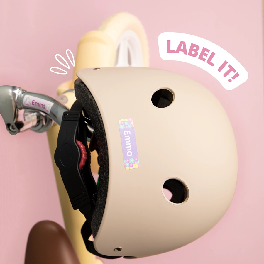 Beige helmet with a personalised name label featuring 'emma' and colorful flower designs