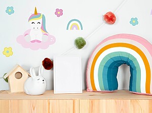 Colourful children' room decor with a rainbow pillow, unicorn wall stickers, and playful flower designs.