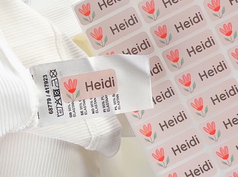 Pink personalised name label with a tulip design and the name Heidi, applied to a clothing tag on a white garment