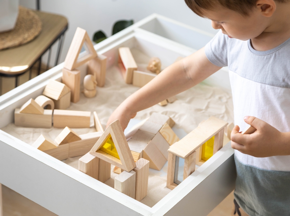 Child playing with wooden building blocks at a sensory table