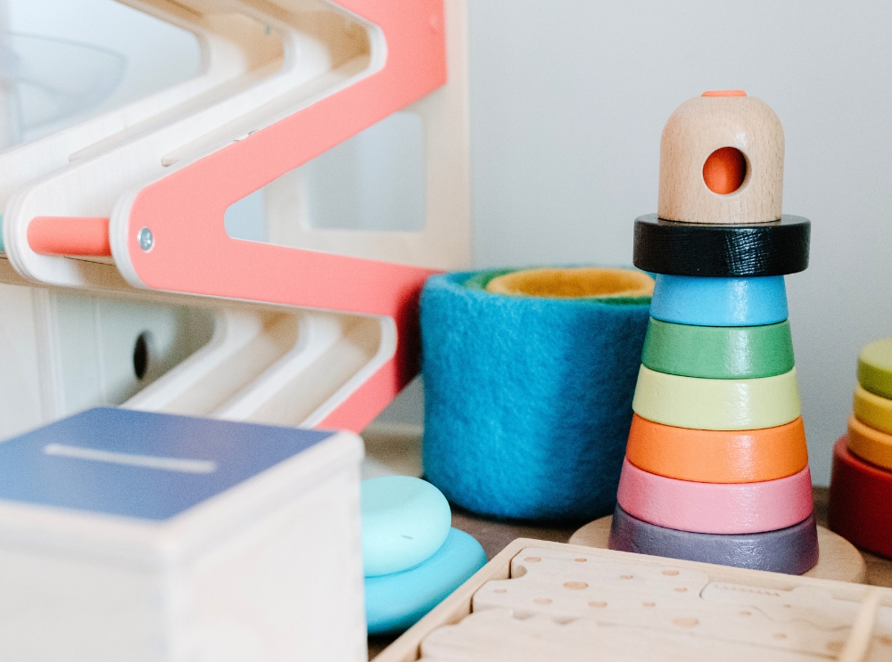 Close-up of colourful wooden preschool toys, including stacking rings, bowls, and a marble run