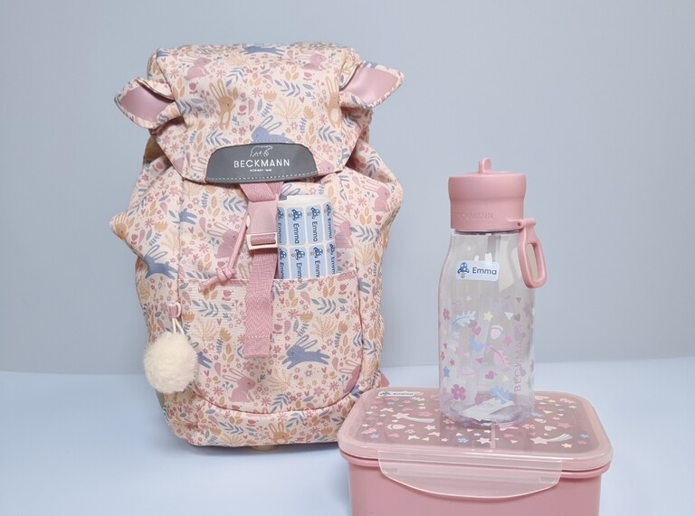 Matching floral backpack, water bottle, and lunchbox labeled with personalized name stickers for school or daycare