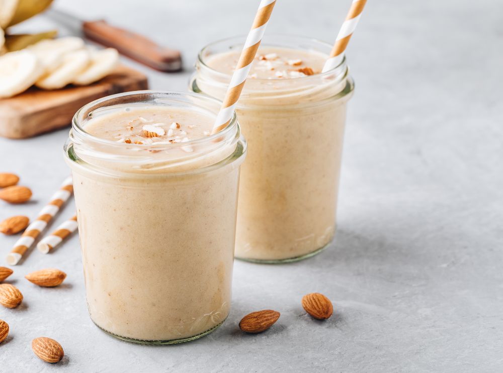 Banana and almond smoothie in a clear glass with a brown straw