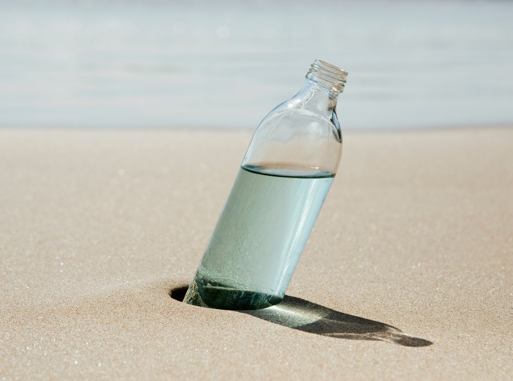 Water bottle standing at a beach in sand
