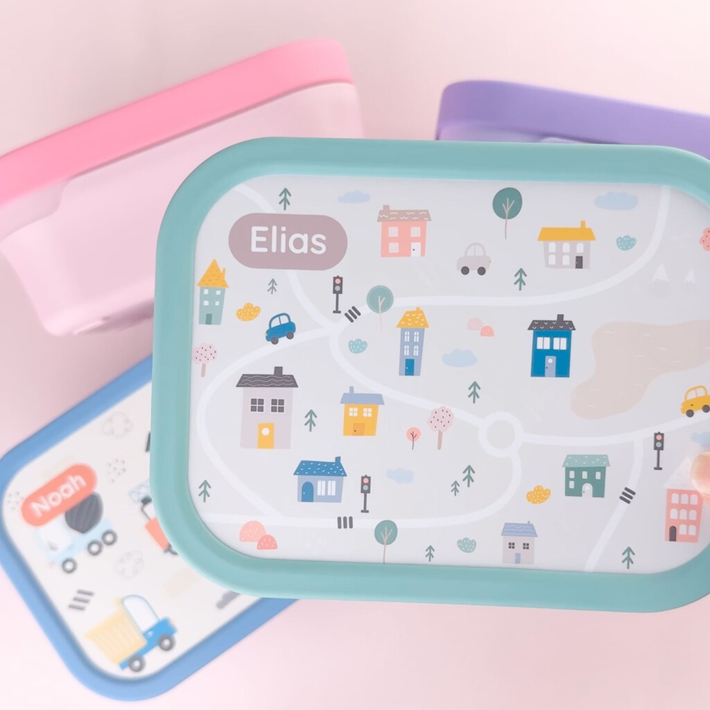 Colourful lunch boxes with playful city map design and personalised name on the lid