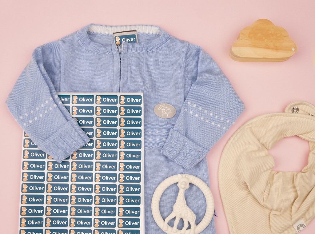 Flatlay of extra clothes and items for daycare, personalised with a set of name labels with the name "oliver"