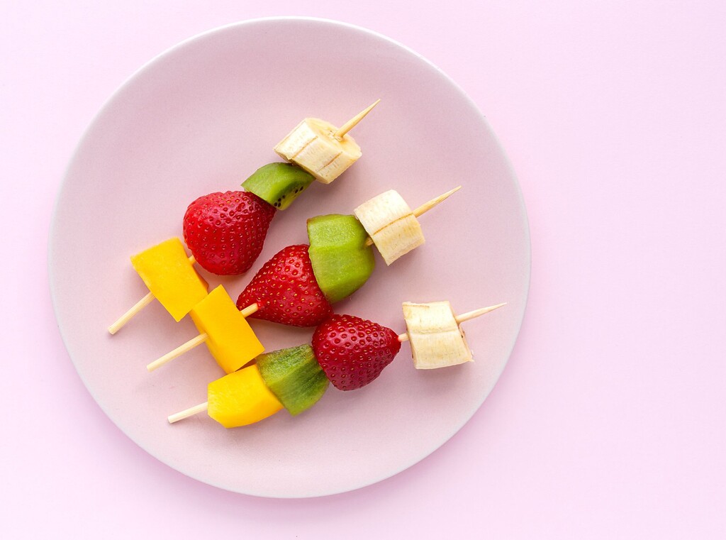Fresh fruit skewers with banana, kiwi, strawberry, and mango served on a plate.