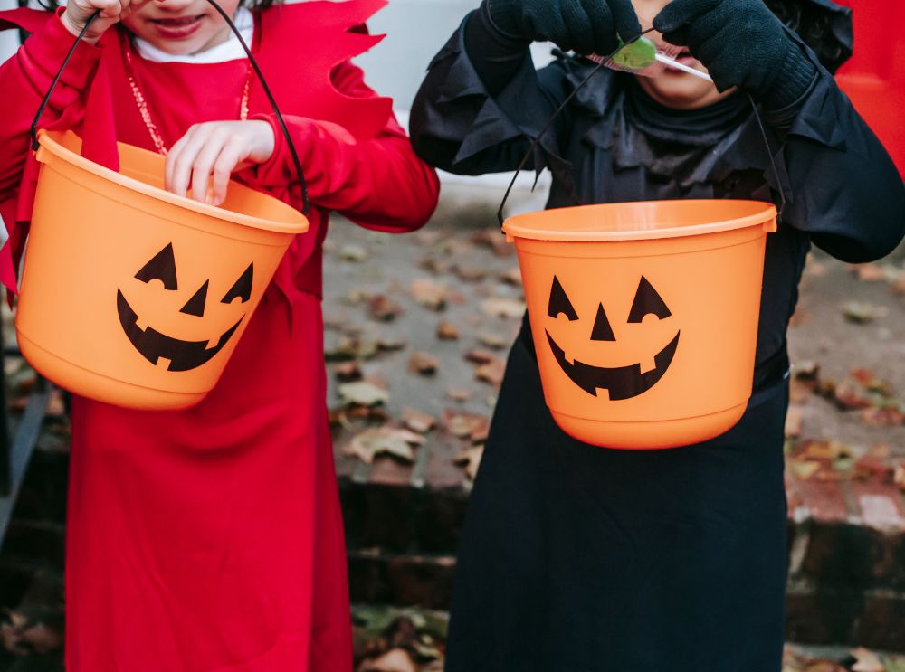 Children carrying orange pumpkin buckets for trick-or-treating