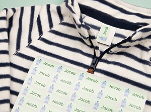 Sheet of green namelabels with a hippo design placed on a striped kids' shirt
