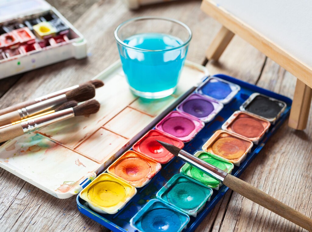 Watercolour paint set with brushes and a glass of water, ready for a kids’ craft activity.