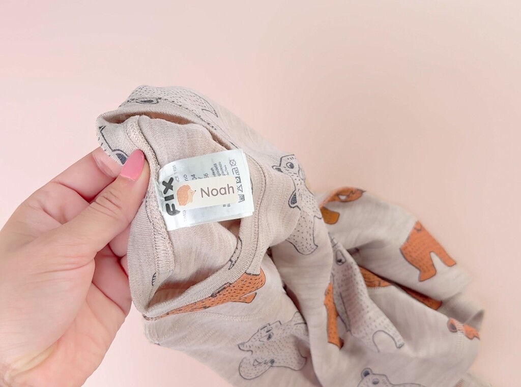 Close-up of a personalized name label with the name Noah applied to the care tag inside a child’s beige garment.