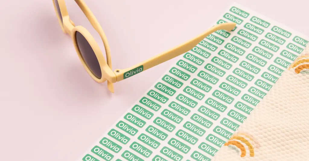 Personalised green mini label reading olivia on yellow sunglasses, with a matching sticker sheet and summer accessories