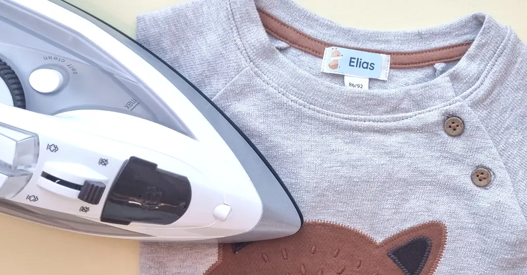 How to remove iron-on labels: step-by-step guide 1 Iron-on name label with a fox design applied to a gray baby shirt, shown next to an iron