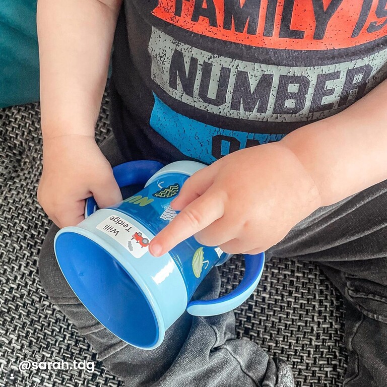 Small child sticking a name label on a drinking bottle