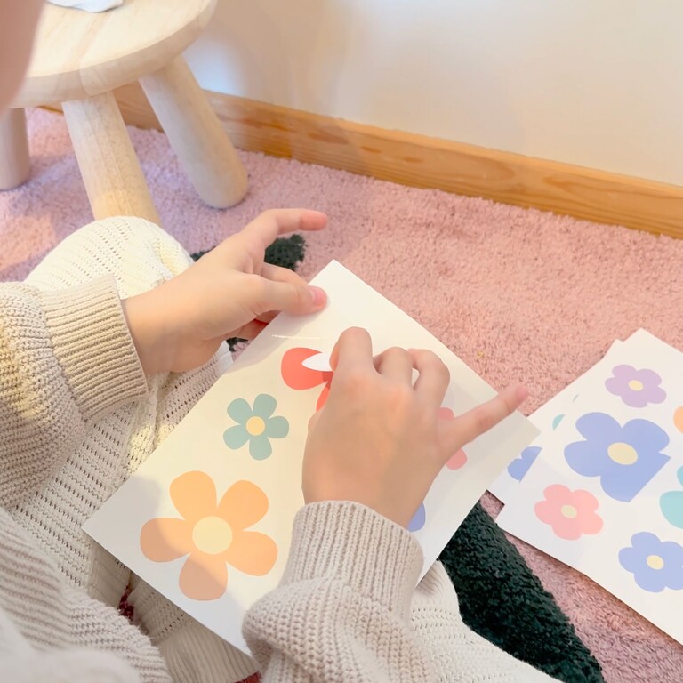 Daisy (multicoloured) wall stickers being peeled off the sheet by a child