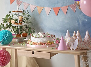 Party table with cake, cupcakes, sweets and party hats at a children's birthday party