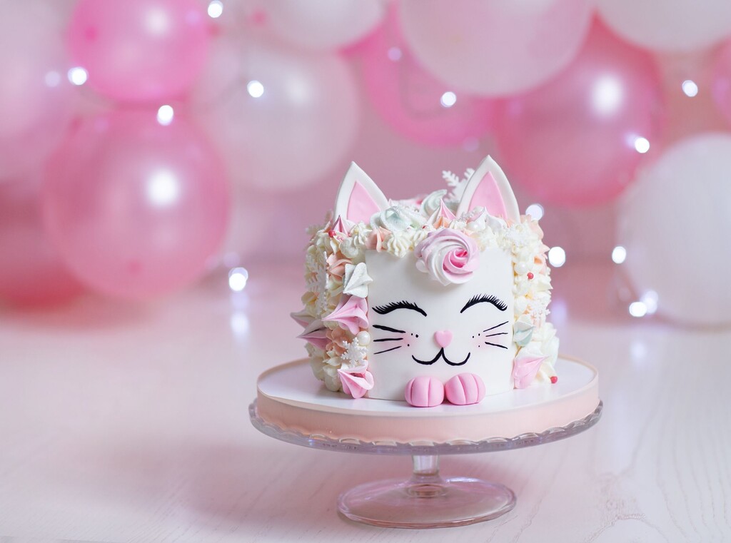 Easy and creative kids’ birthday party ideas 3 Cat-shaped birthday cake on a cake stand with pink balloons in the background