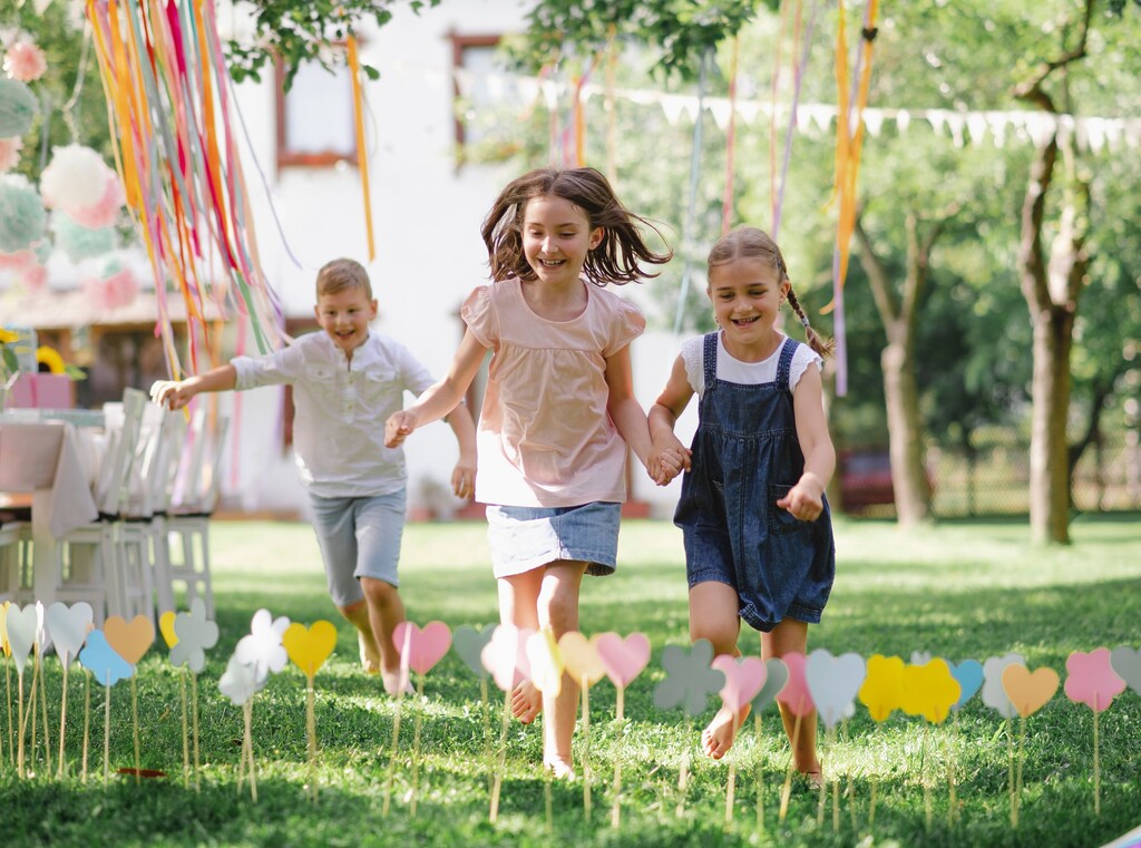 Children running together at an outdoor birthday party with balloons and decorations