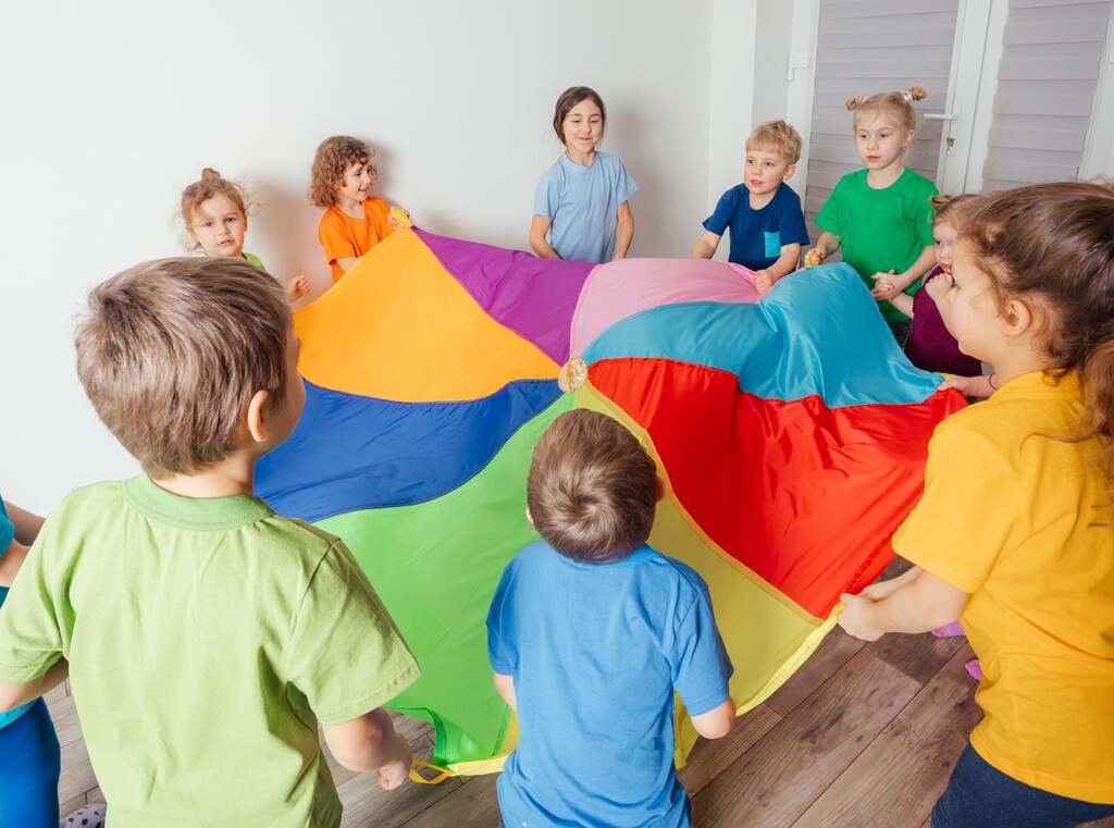 Children playing together with a colourful play cloth at a birthday party