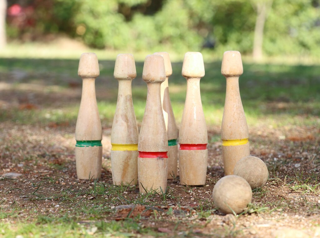 Wooden skittles and wooden balls set up outdoors for a game of skittles